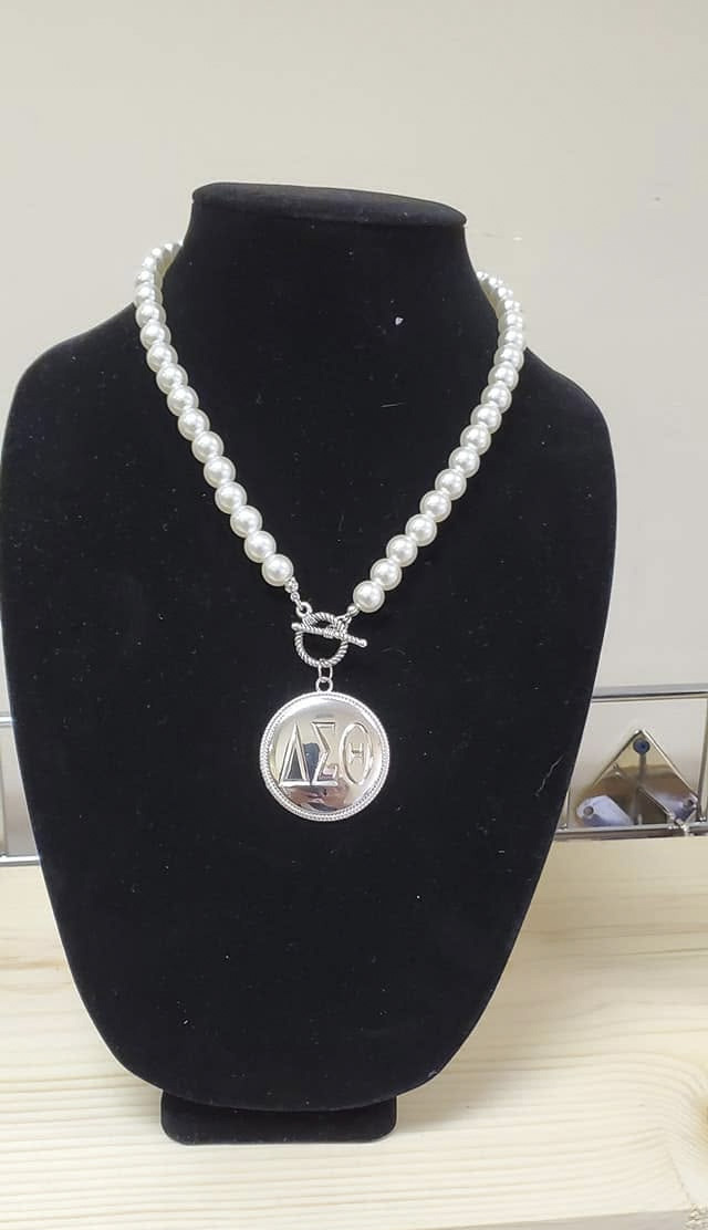 White pearl necklace with silver toggle clasp and round ΔΣΘ medallion pendant