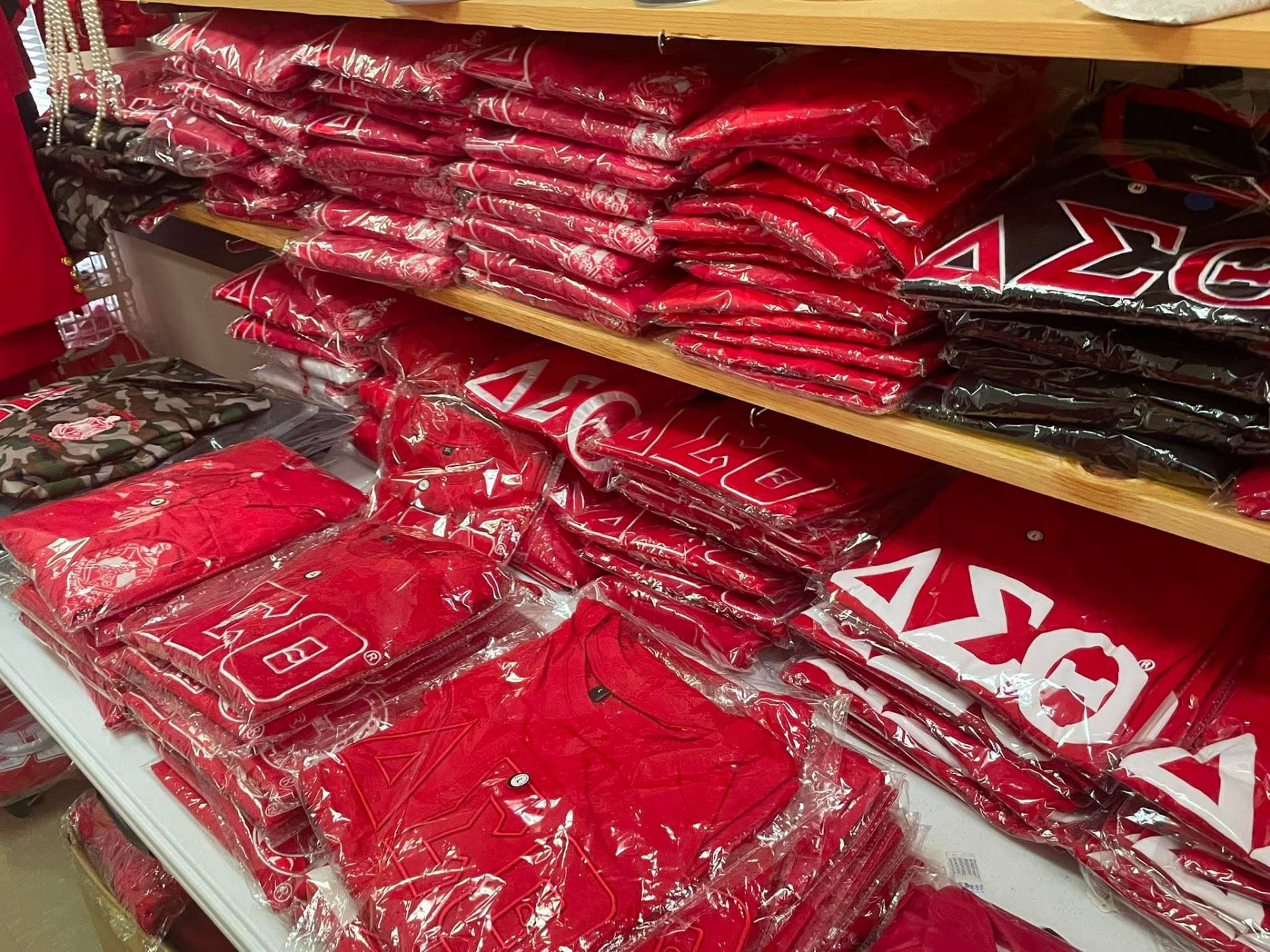 Shelves filled with packaged Delta Sigma Theta T-shirts and jerseys inside the A & J Elite Greek Store