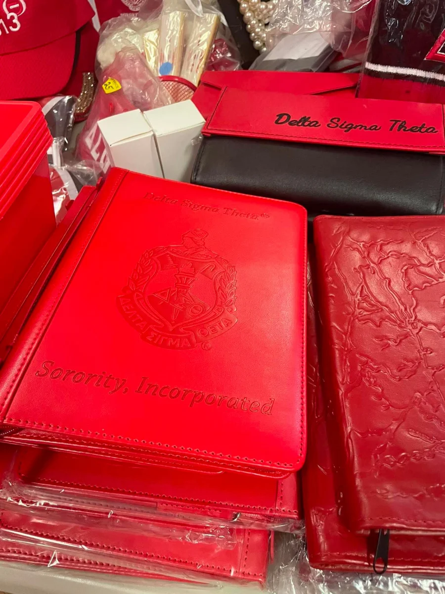 Stack of crimson Delta Sigma Theta ritual covers with embossed crest and Sorority, Incorporated lettering