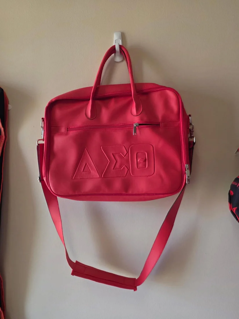 Red Delta Sigma Theta laptop bag with embossed ΔΣΘ letters, top handles and adjustable shoulder strap
