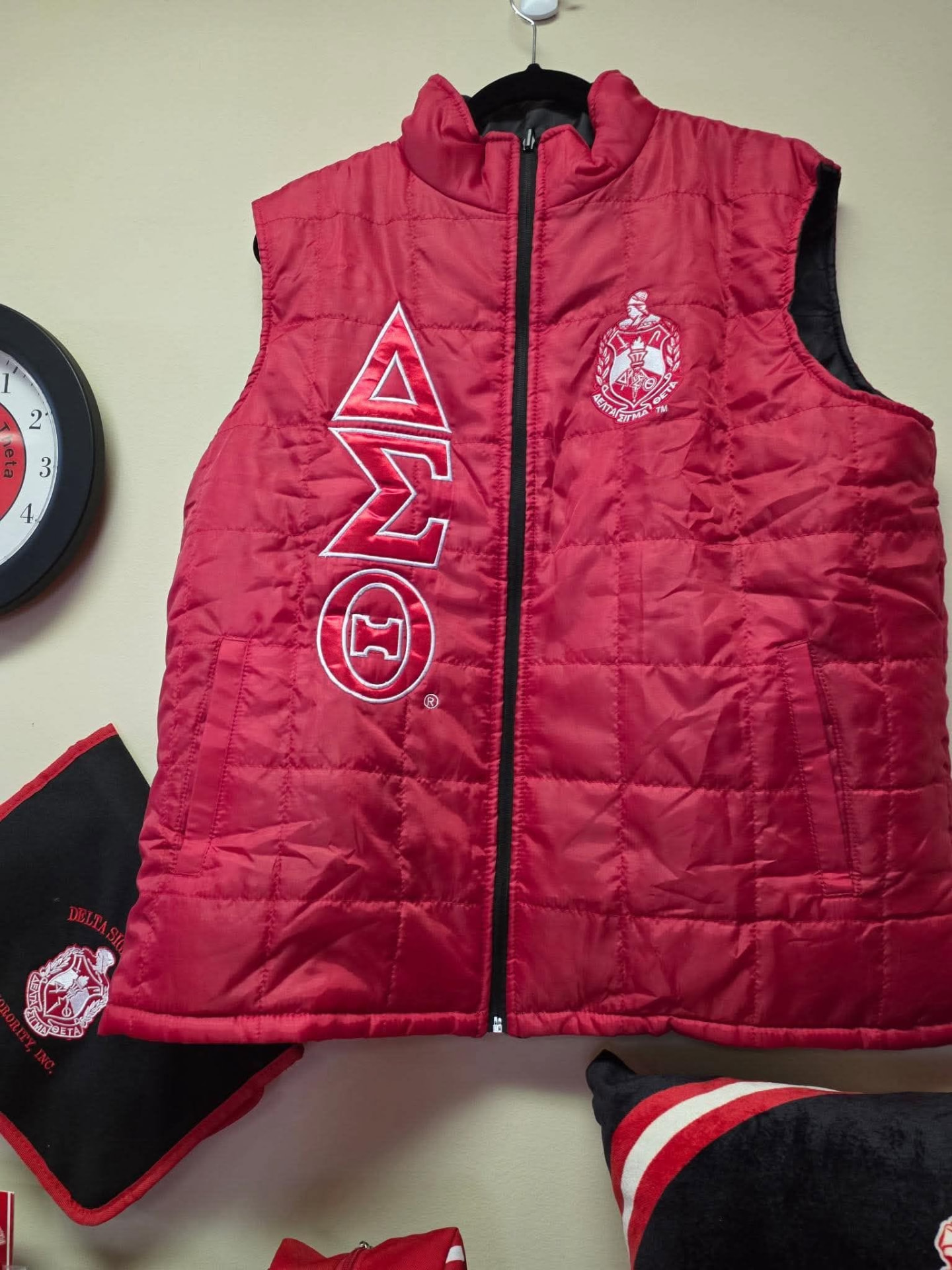 Red Delta Sigma Theta puffer vest with vertical red ΔΣΘ symbols, white outline stitching, and the embroidered Sorority crest