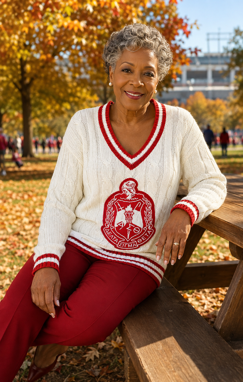 Delta legacy alumna in ivory and crimson cable-knit crest sweater on an autumn campus