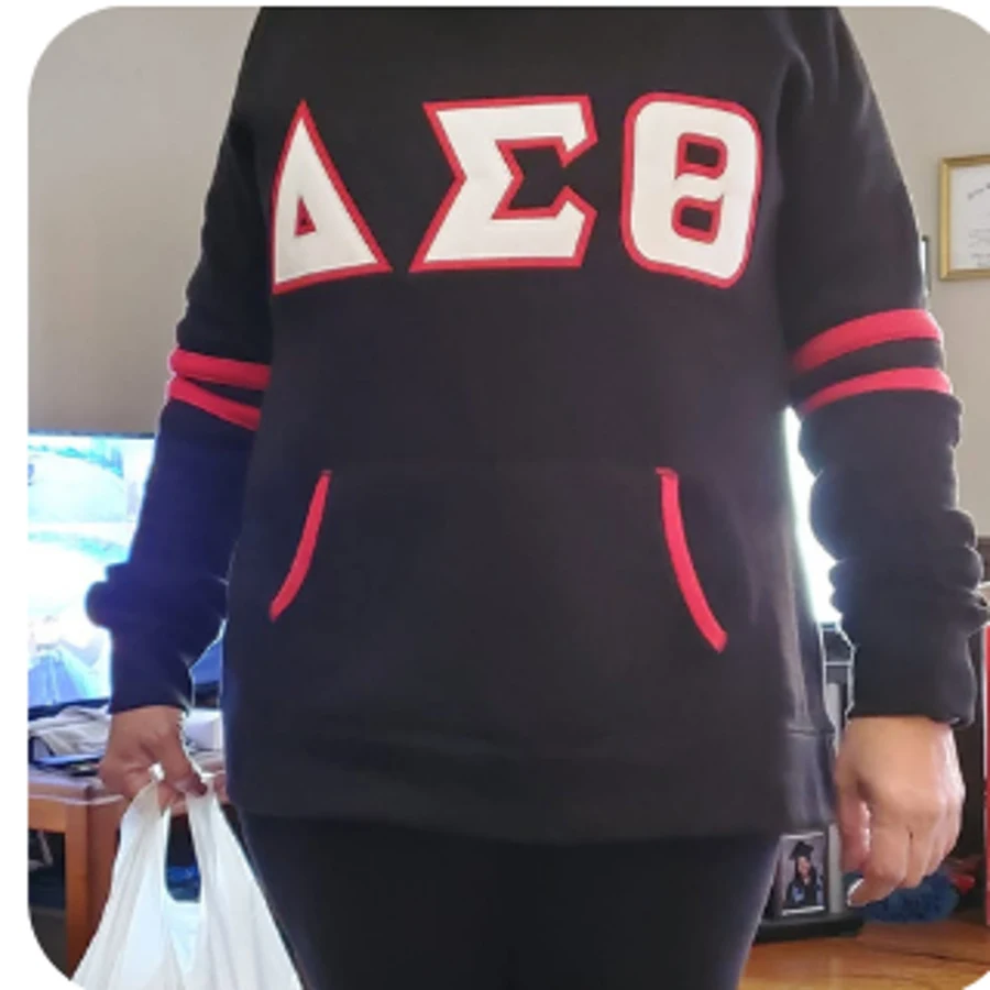 Black tunic-length pullover with white DST letters and red sleeve stripes