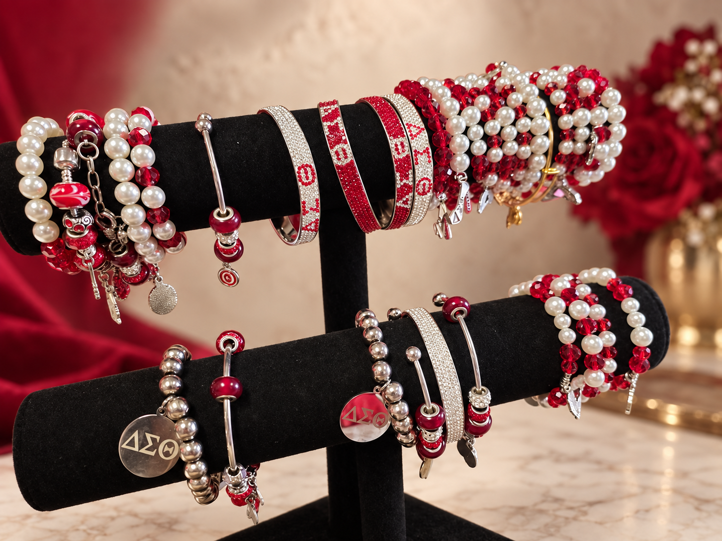 Assorted crimson, white, silver, pearl, crystal and Delta charm bracelets displayed on black stands