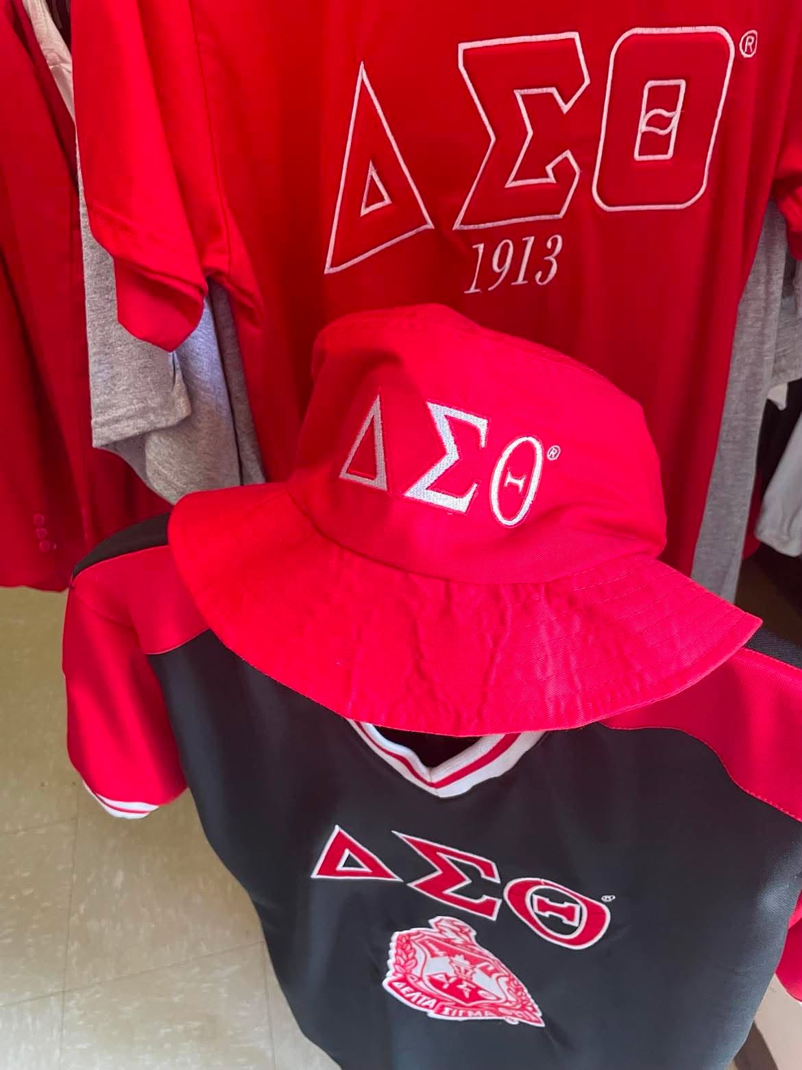 Crimson Delta Sigma Theta bucket hat with embroidered ΔΣΘ symbols, displayed with Delta apparel in the A & J Elite Greek Store