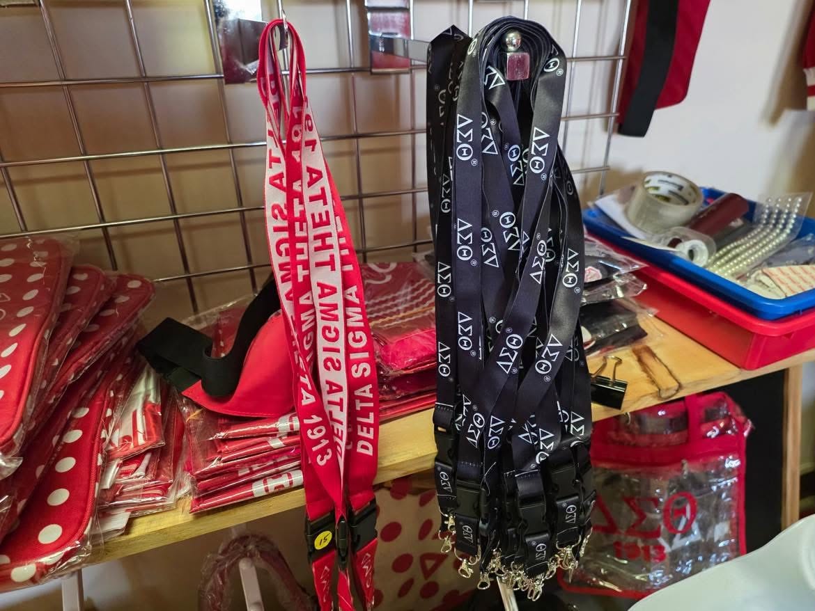 Delta Lanyards in two styles — crimson with Delta Sigma Theta lettering and black with a repeating ΔΣΘ pattern — hanging in the A & J Elite Greek Store