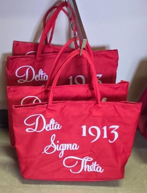 Red canvas totes with flowing white Delta Sigma Theta 1913 script lettering