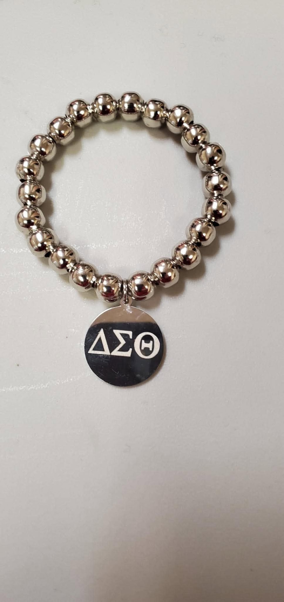 Silver beaded stretch bracelet with a round ΔΣΘ disc pendant engraved with the Delta Sigma Theta Greek letters