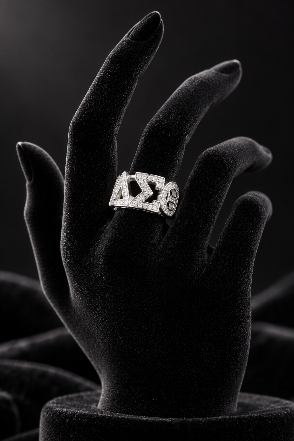 Crystal-paved ΔΣΘ statement ring in silver, displayed on a black velvet hand
